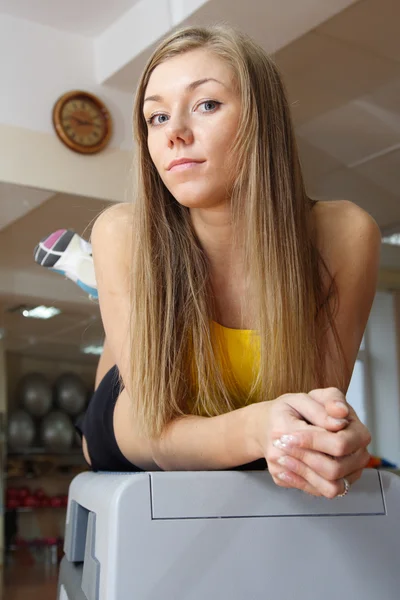 Prachtige blond meisje, zittend op stappen in gym Stockfoto