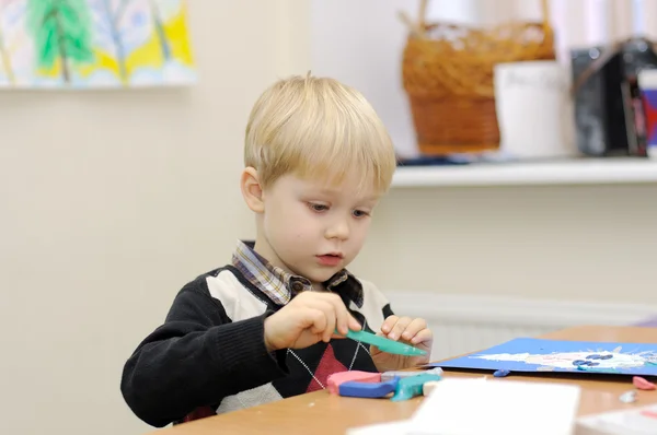 stock image A little boy at the table molds from clay painting