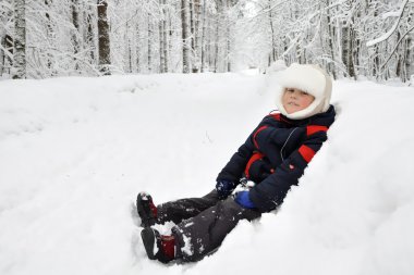 Little boy playing in the snow in the park in winter clipart