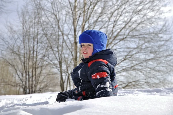 A little boy on a big snowdrift in winter snow throws. — Stock Photo, Image