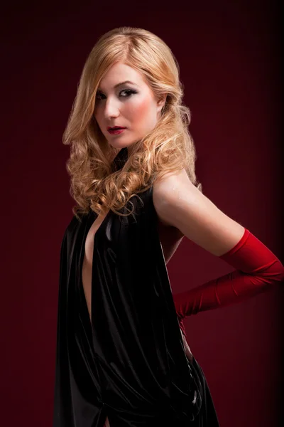 Perfect blonde in a black dress on red — Stock Photo, Image