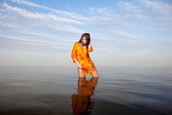 Menina posando na água ao pôr do sol — Fotografia de Stock
