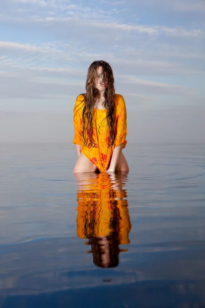 Lány pózol a vízben naplementekor — Stock Fotó