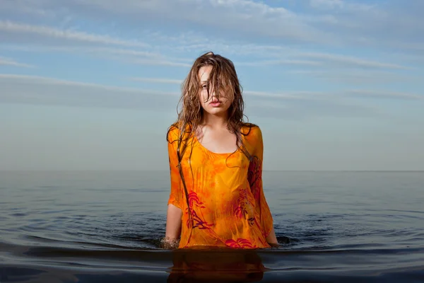 Dívka pózuje ve vodě při západu slunce — Stock fotografie