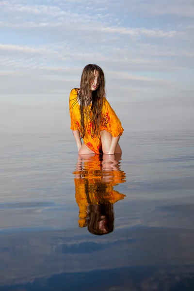Dívka pózuje ve vodě při západu slunce — Stock fotografie