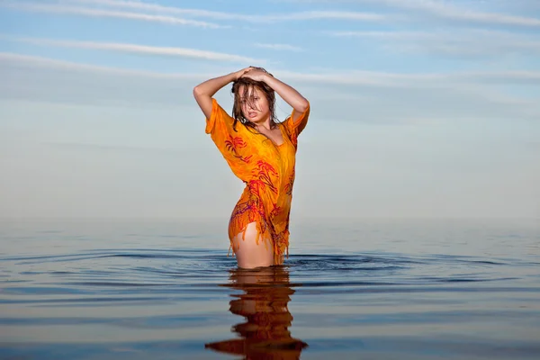 Fille posant dans l 'eau au coucher du soleil — Photo