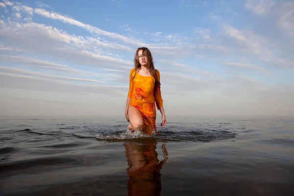 Flicka poserar i vattnet vid solnedgången — Stockfoto