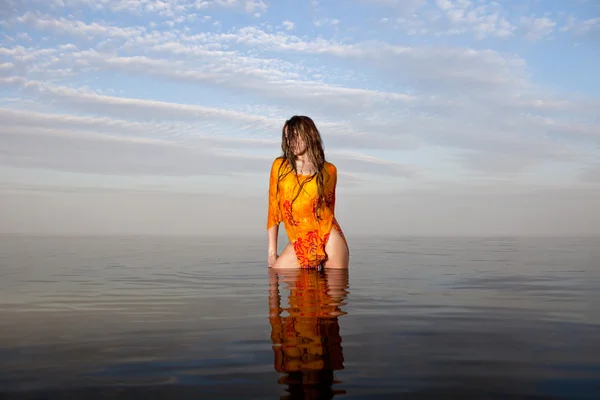 Дівчина позує у воді на заході сонця — стокове фото