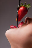 Mädchen isst Erdbeere mit Schokosauce