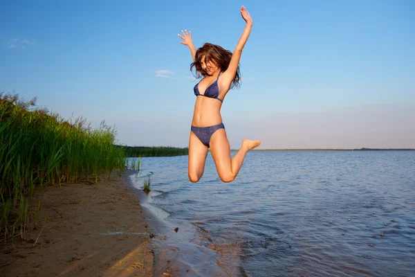 Jonge vrouw op de lucht en water achtergrond — Stockfoto