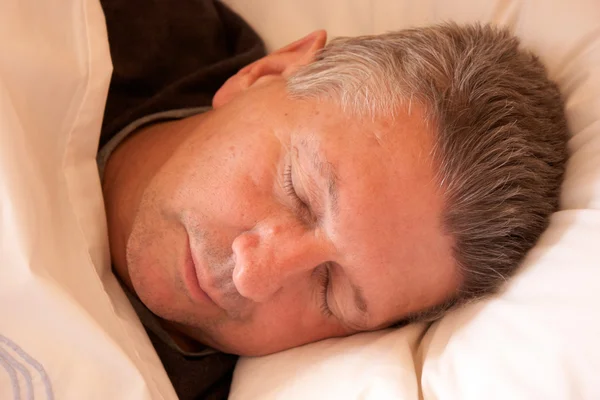 Mature man clothed and asleep in bed