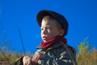 Boy in cap and red comforter clipart