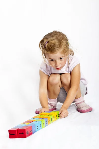 Menina feliz brincando com blocos de madeira coloridos — Fotografia de Stock