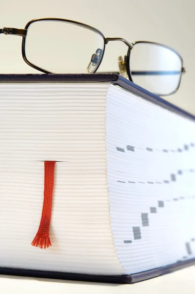 Thick book with reading glasses and bookmark — Stock Photo, Image