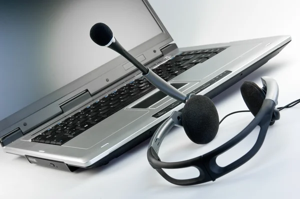 Headset com laptop em segundo plano — Fotografia de Stock