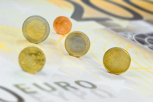 Euro coins rolling over a 200 euro banknote — Stock Photo, Image