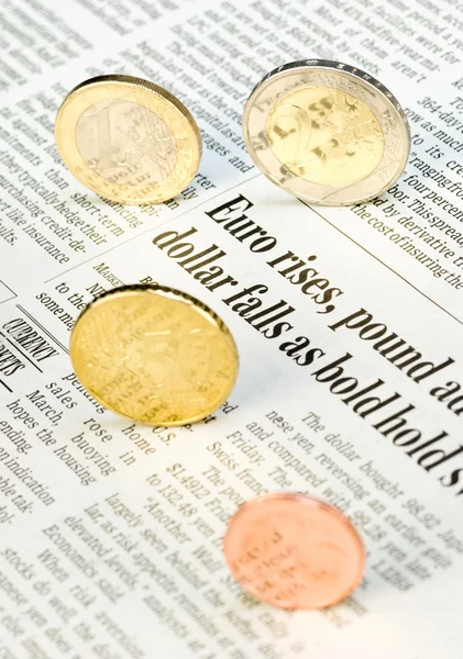 Monedas en euros rodando sobre un periódico —  Fotos de Stock