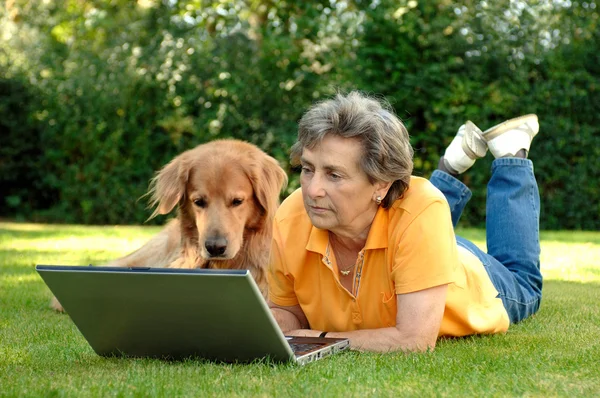 Mulher sênior com seu cão em um laptop — Fotografia de Stock