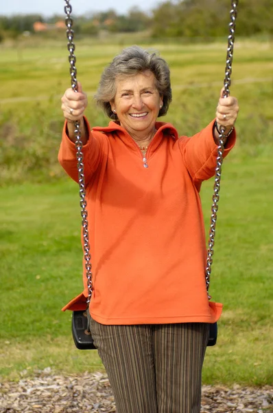 Senior woman on a playground swing — Stock Photo, Image