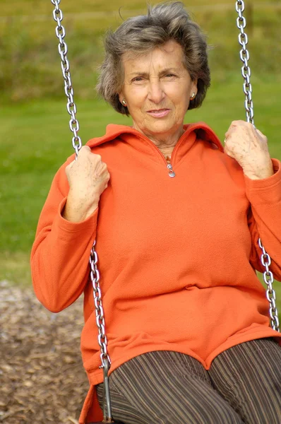 Stock image Senior woman on a playground swing