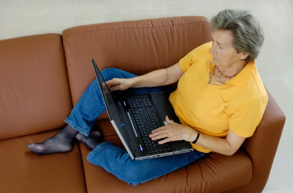 stock image Senior woman with laptop on a couch