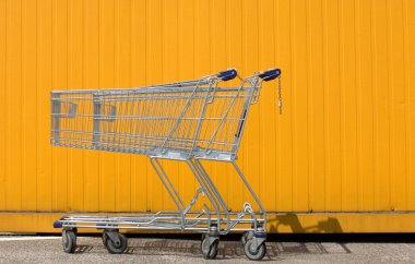 Two empty shopping carts in front of a yellow wall clipart