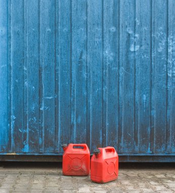 iki kırmızı benzin kutu mavi konteyner duvarın önünde