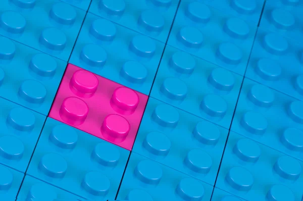 stock image Pink building block in a field of blue one