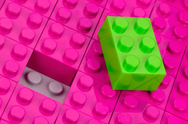 Green building block in a field of pink one — Stock Photo, Image