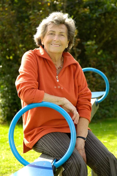 Senior woman on a playground seesaw — Stock Photo, Image