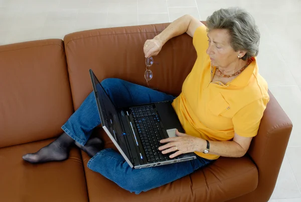 stock image Senior woman with laptop on a couch