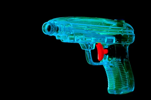 Niebieski pistolet na wodę z czerwony spust na ziemi czarnej — Zdjęcie stockowe