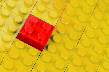 Red building block in a field of yellow ones clipart