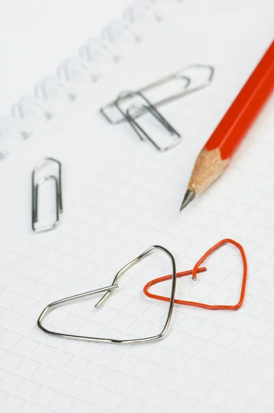 Paper clip formed as a heart with red pencil — Stock Photo, Image