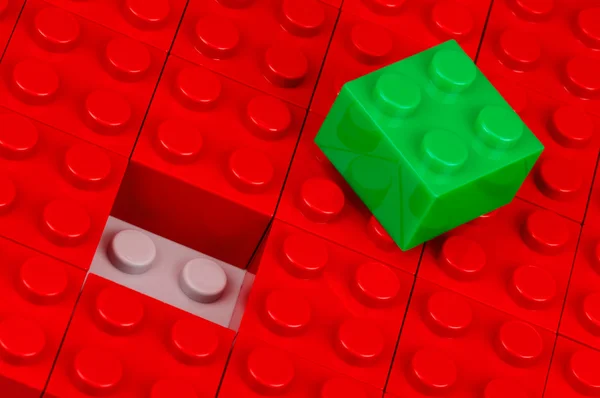 Green building block in a field of red ones — Stock Photo, Image