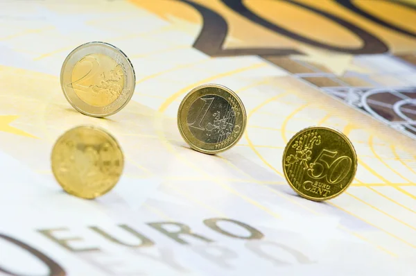 Monedas en euros rodando sobre un billete de 200 euros —  Fotos de Stock