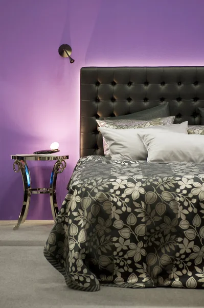 Кровать перед фиолетовой стеной — стоковое фото