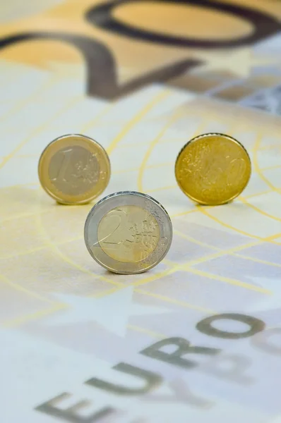 Monedas en euros rodando sobre un billete en euros — Foto de Stock