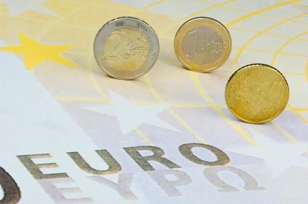 Монеты евро катятся по банкноте евро — стоковое фото