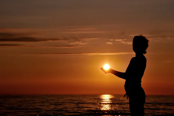 Stock image Woman silhouette at sunset as like holding the sun