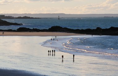 walking at the beach of Saint-Malo at sunset. clipart