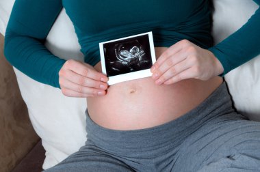 Pregnant woman holding ultrasound photo clipart