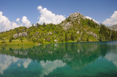 Colorful Sary-Chelek Lake with mountains, sky and clouds clipart