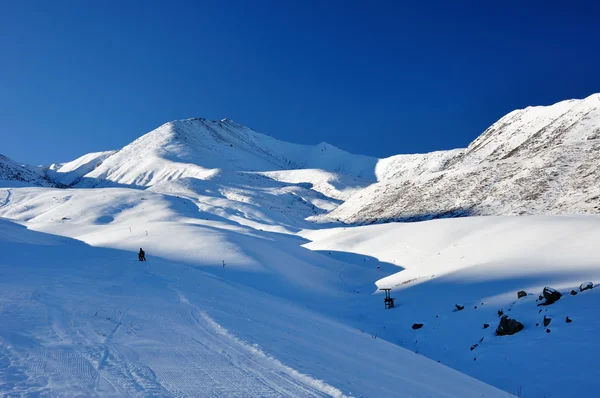 Vinter i berg med blå himmel och skidåkare — Stockfoto