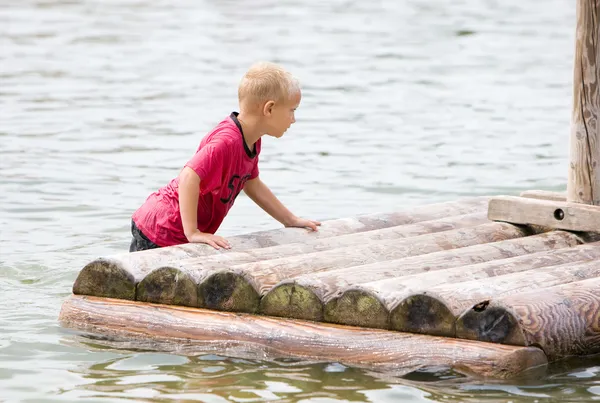 年轻的男孩推他的木筏 — 图库照片