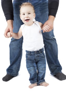 Baby boy is trying to walk with his parent. clipart