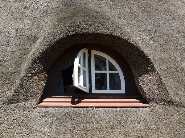 Schönes Fenster in einem Haus mit Schilfdach Stockbild