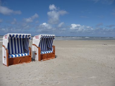 Beautiful blue sky with two beachchairs on an island clipart