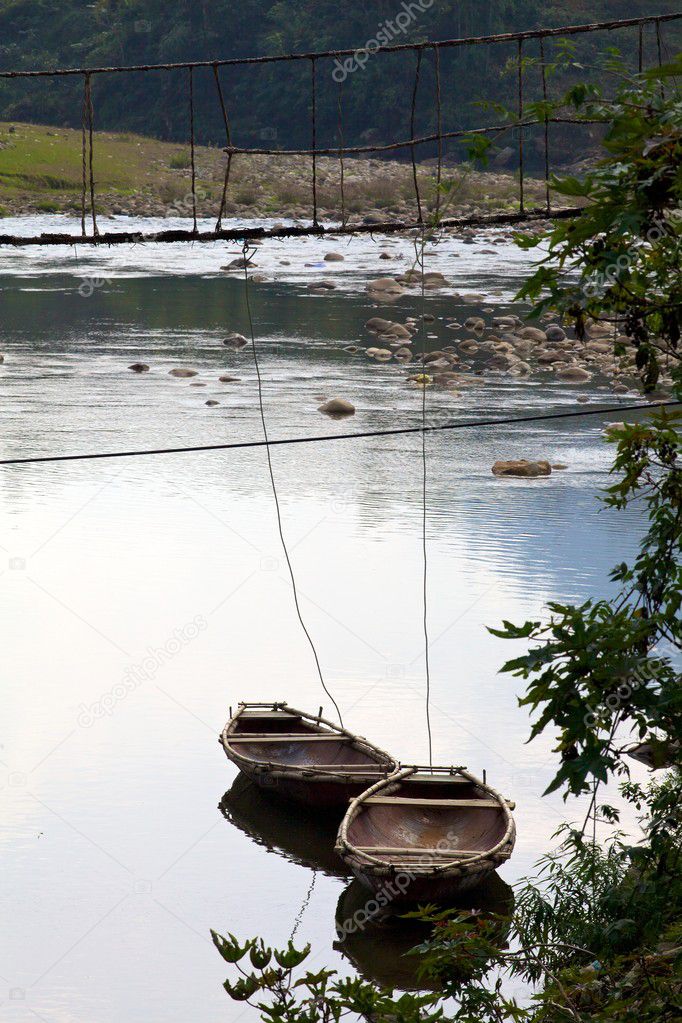 Two boats tied to old suspension bridge in Ta Van Village, Vietnam