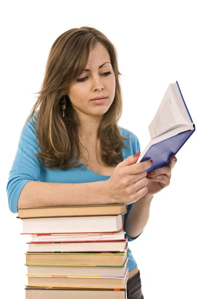 Menina bonita cuidadosamente lendo um livro, cercado por livros — Fotografia de Stock